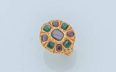 18 karat (750 thousandths) yellow gold ring in Byzantine style, set with a faceted garnet, in a circle of alternating emeralds and garnets in closed settings. The bezel is carved with a decoration of acanthus leaves.