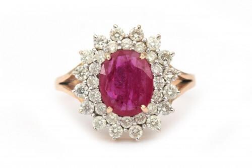 A 14 karat gold ruby and diamond cluster ring. Featuring an oval cut ruby of ca. 1.40 ct. in a surround of thirty two brilliant cut diamonds, ca. 1 ct. in total, ca. I-J, ca. VS-SI. Gross weight: 6.3 g.