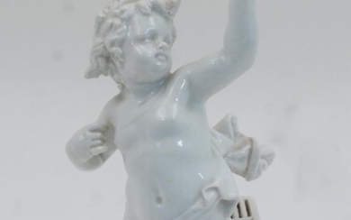 A German porcelain white-glazed figure of a cherub, 20th century, partially draped and holding aloft a bird in his left hand, with a square cage at his feet, atop chamfered base, filled, 22cm high Provenance: Works of Art from the Schroder...