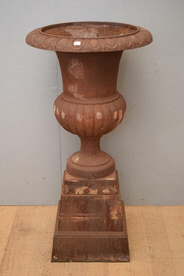 A LARGE CLASSICAL STYLE CAST IRON URN ON BASE (113H X 58W CM) (PLEASE NOTE THIS HEAVY ITEM MUST BE REMOVED BY CARRIERS AT THE CUSTOM...