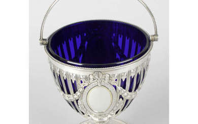 A Victorian silver pierced and swing-handled pedestal sugar basket with blue glass liner.