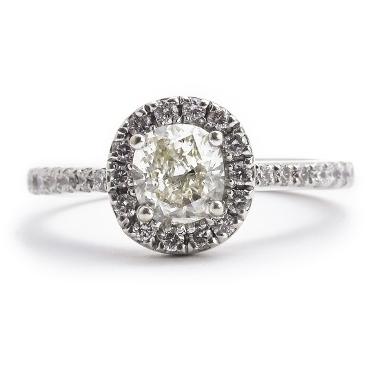 A diamond ring set with a fancy yellow diamond weighing app. 0.63 ct. encircled and flanked by numerous brilliant-cut white diamonds, mounted in 18k white gold.