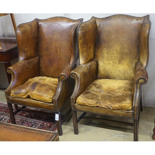 A pair of George III style tanned leather wing armchairs ...
