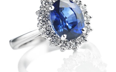 A sapphire and diamond ring set with an oval-cut sapphire weighing app. 3.84 ct. encircled by numerous brilliant-cut diamonds weighing a total of app. 0.58 ct., mounted in 18k white gold. Colour: Wesselton (H). Clarity: VS. Size 52.