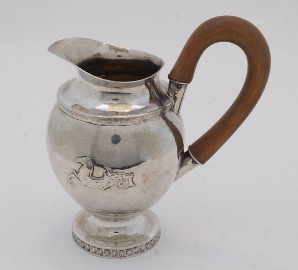 A small Continental white metal jug, probably Italian, early 19th century, of ovoid form with two applied hippocampus to body, on circular base with engraved floral motifs, having wooden handle, 16.7cm high