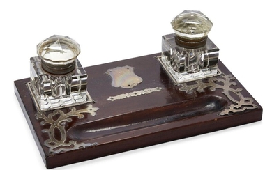 An Edwardian silver mounted wooden inkstand, London, c.1903, M Chapman, Son & Co Ltd., the two square glass inkwells with cut glass domed lids and square cut bases, the inkstand with vacant silver shield cartouche and applied silver decoration to...
