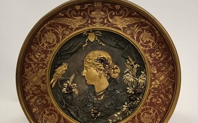 Dish in wrought brass with central decoration of a bronze medallion bearing a profile of a woman in the antique style among plants and facing a domestic cockatoo.