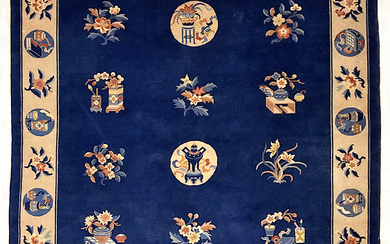 Tappeto Pekino, Cina. Secolo XX. Decoro con simboli taoisti e rami fioriti su fondo blu. Bordura con tondi e fiori…