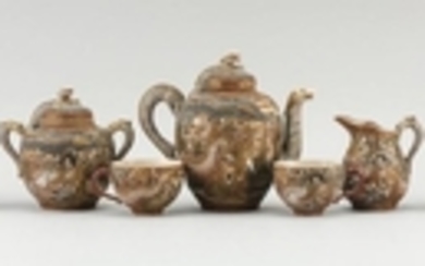 SATSUMA POTTERY TEA SET In lohan and relief dragon design. Consisting of covered teapot, covered sugar bowl, creamer, five cups and...