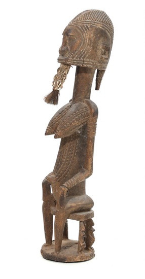A 20th century carved wood seated female figure with cowrie shells and...