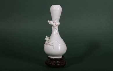 A CHINESE WHITE-GLAZED GARLIC MOUTH 'DRAGON' VASE. Qing Dynasty. The pear-shaped body with a tall neck and a bulbous rim applied with two sinuous dragons and decorated with a pale cream glaze, together with a wood stand, 15.5cm H. (2) 清 白釉龍紋蒜頭口瓶連木座