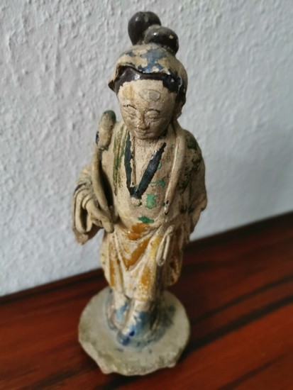 A Chinese 19th century stoneware figurine partly glazed in green, blue and yellow. H. 22 cm.