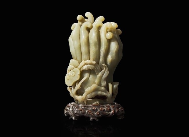 A Chinese carved celadon jade Buddha’s-hand citron with carved wood stand, Qing dynasty