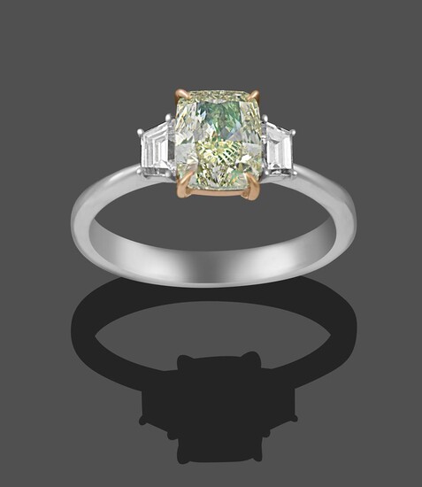 A Diamond Three Stone Ring, the central fancy light greenish-yellow cushion modified brilliant...