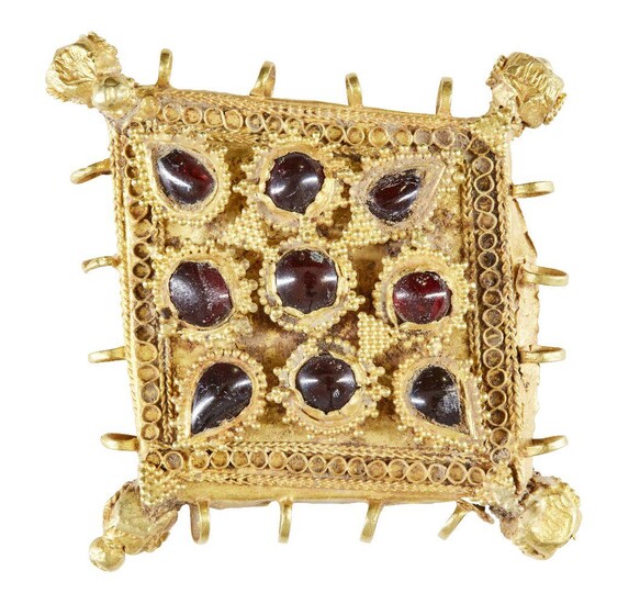A garnet-set gold pendant element, Iran, 12th century, of diamond shape and box construction, the central field set with nine small garnets within raised frames set with, the base with wire and chain work, the four corners set with faceted ball...