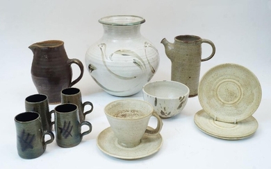 A group of studio pottery, 20th century, to include a Leach Pottery stoneware jug with brown glaze, mark for St Ives and impressed 'ENGLAND', 20cm high, a mottled buff coloured jug lacking cover, indistinctly marked, four pottery mugs signed...