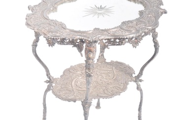 A late 19th Century Continental silver plated side occasional table / wine or lamp table. Inset glass mirror panel to top with scrollwork repousse frame. Raised on four shaped figural legs united by an under tier. Makers stamp to underside. Measures...