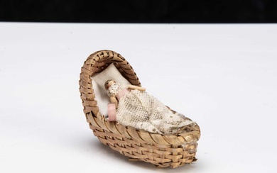 A miniature Grodnerthal dolls’ house doll in cradle