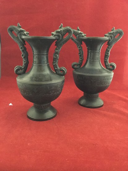 A pair of Chinese bronze vases, each with two dragon handles...