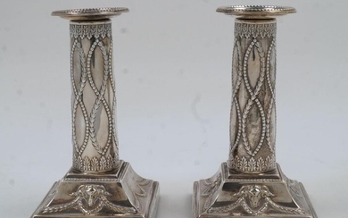 A pair of Edwardian Adam Revival silver candlesticks, London, 1901, Thomas Bradbury & Sons, of columnar form with beaded edges and chased with rams heads and swags, filled, 13.5cm high