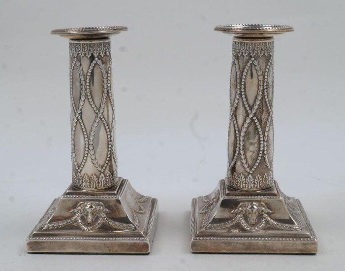 A pair of Edwardian Adam Revival silver candlesticks, London, 1901, Thomas Bradbury & Sons, of columnar form with beaded edges and chased with rams heads and swags, filled, 13.5cm high