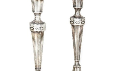 A pair of silver candlesticks, Birmingham, c.1921, Ellis & Co., designed in the Adam style, the tapering reeded stems to octagonal feet with acanthus tip surround and beaded borders, each conforming capital to a garland-decorated knop, 28.5cm high...