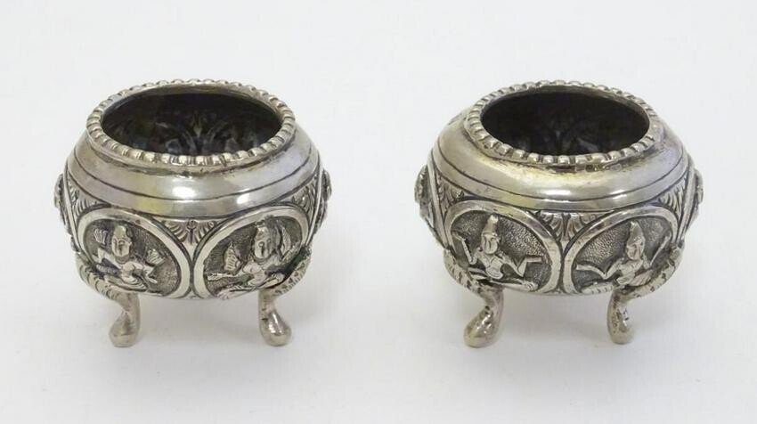 A pair of white metal salts with deity decoration.