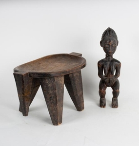 A tribal stool with concave seat on tapering supports