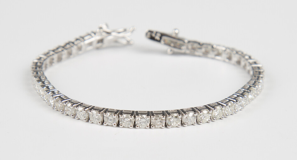 An 18ct white gold and diamond bracelet, claw set with a row of circular cut diamonds, on a snap cla