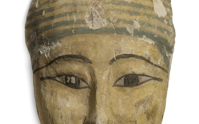 An Egyptian wooden mummy mask with stucco, yellowish skin, red outline for lips and painted eyes, with striped headgear. Late period 712–30 BC. L. 23 cm.