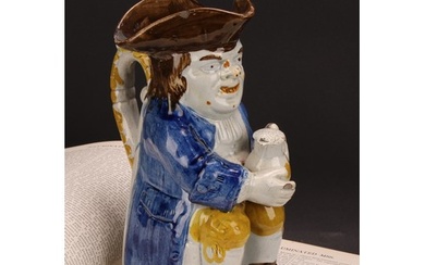 An early 19th century Prattware Toby jug, seated holding a j...