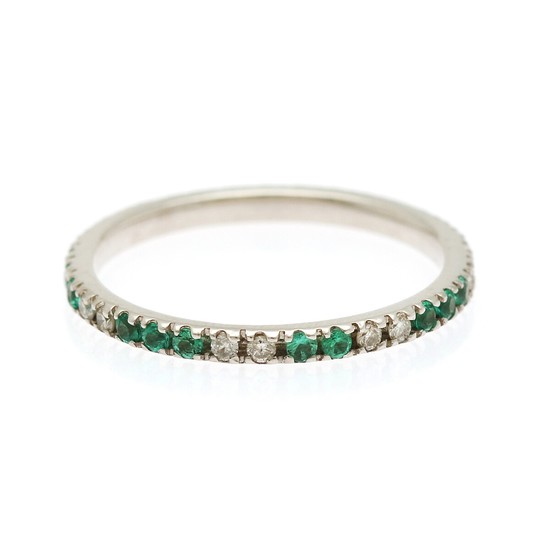 An emerald and diamond eternity ring set with numerous circular-cut emeralds and brilliant-cut diamonds, mounted in 18k white gold. Size 52.