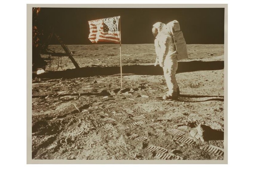 Buzz Aldrin posing for a photograph beside the US flag