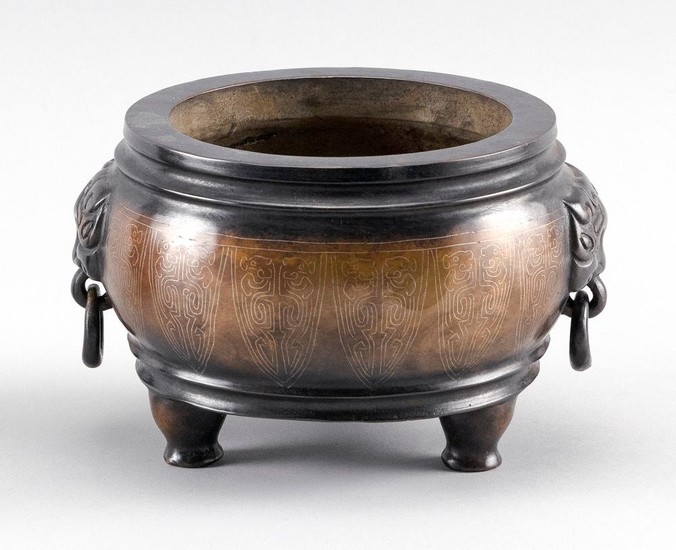 CHINESE BRONZE CENSER In squat form, with mask handles, silver inlaid lappet design about the body, and tripod base.
