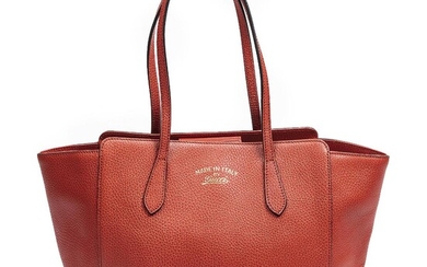 Gucci A “Swing Tote” bag of red leather with gold tone hardware,...