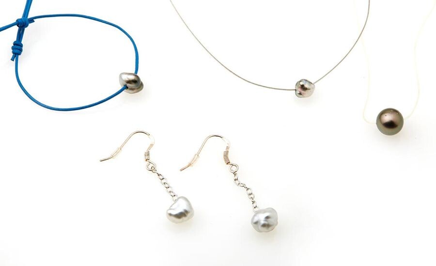 Lot comprising : A steel cable necklace, decorated with a Keshi pearl An adjustable blue leather necklace, decorated with a Keshi pearl. A transparent cable necklace, decorated with a Tahitian pearl A pair of 800/°° silver earrings decorated with a...