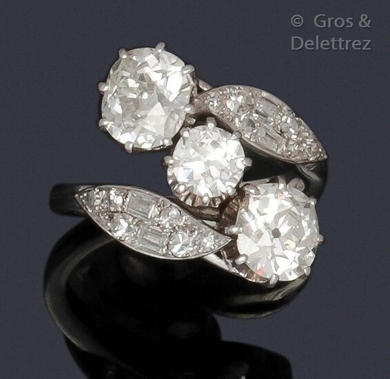 Ring " Toi and Moi " in white gold, made up of two cushion-shaped diamonds set in a foliage setting of baguette-cut and brilliant-cut diamonds, in an entourage of foliage. Diamond weight principaux : about 1.60 carat each, the central one about 0.80...