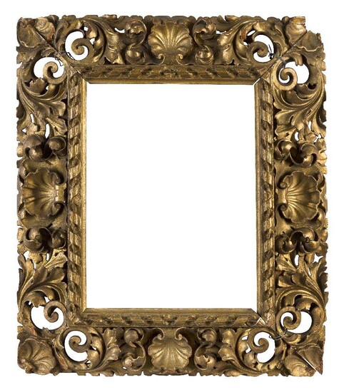 A Carved and Gilded Florentine Style Frame of Reverse Profile, early-mid 19th century- with cavetto sight, raked ribbon-and-stick, the back edge with pieced foliate scrollwork in high relief and shell centres and corners, 36 x 27 cm. (sight).