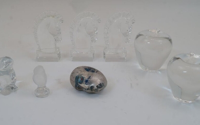 A group of clear glass paperweights, 20th century, to include two modelled as apples, each 10cm high, three modelled as horse heads in profile atop hexagonal bases, one with etched dedication to the base 'In Appreciation Marsh & McLennan June 5...