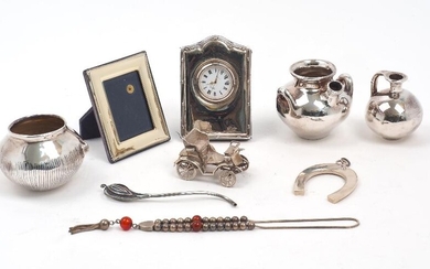 A group of silver and metal oddments, comprising: a silver easel back clock, Sheffield, 1994, Carr's of Sheffield; a set of three small vases designed as various ceramic vessels, all stamped .1000, assumed plated; a miniature photo frame, stamped...