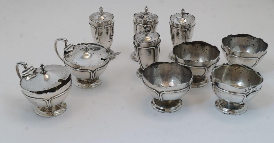 A group of silver cruets, Birmingham, 1919, Edward Souter Barnsley, comprising: four pedestal salts, (one with clear glass liner), 4.8cm high; a mustard, 6cm high, (liner deficient) with spoon, and four pepper shakers, approx. 8.5cm high, together...