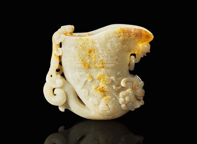 A large Chinese carved pale celadon and russet jade rhyton vessel 青白玉雕