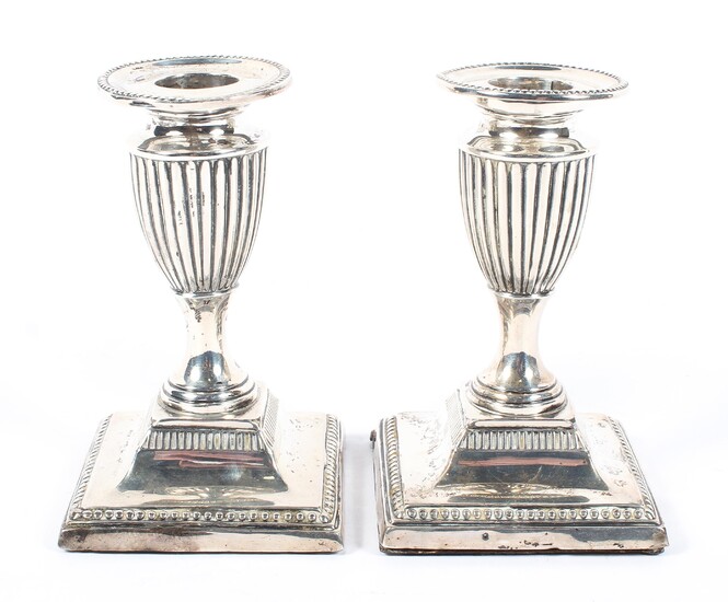 A pair of Edwardian squat silver candlesticks of urn form
