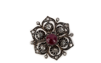 A ruby and diamond brooch, designed as a stylised flower, centring on a cabochon ruby and rose-cut