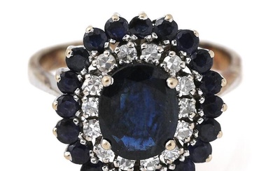 A sapphire and diamond ring set with an oval-cut sapphire encircled by...