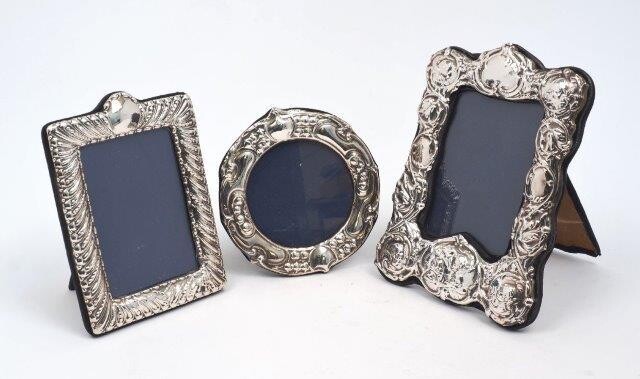 A silver mounted photo frame repousse decorated with putti and foliate scrolls, London, 1978, CJM, 16 x 21.5cm, together with a circular frame, London, 1987, D.R&S., 14.5cm dia., and a third frame by the same maker, London, 1990, 13.2 x 18cm, all...