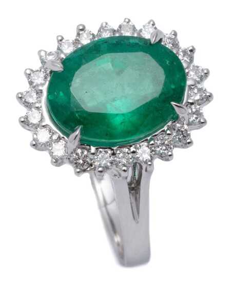 AN 18CT WHITE GOLD EMERALD AND DIAMOND CLUSTER RING; centring an oval cut emerald of approx. 3.30ct to surround of 22 round brillian...