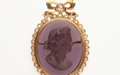 BROCHE en or jaune 750/°° centrée d'une plaque de verre violet figurant un buste de femme collée dans un entourage de roses et perles fines, surmonté d'un noeud serti d'un diamant rose anversoise. H. : 5,5 cm. PB : 25,6 g.