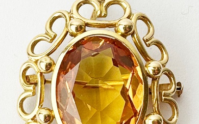 Broche pendentif en or 18k (750e), ornée d'une pierre d'imitation jaune, dans un entourage d'enroulements...