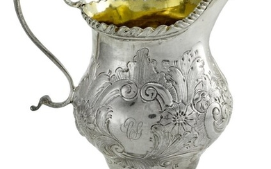 A Repoussé Silver Cream Jug Helmet shaped with gilt interior, hallmark all but obscured by dec...